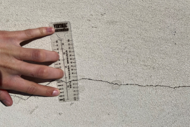 Personne mesurant une fissure avec un mètre ruban Taloc Façades.